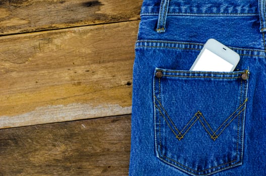 smart phone in pocket jeans on wooden background