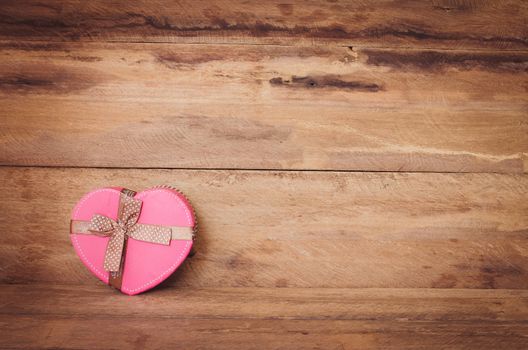 Heart shaped Valentine's Day gift box on wooden background.