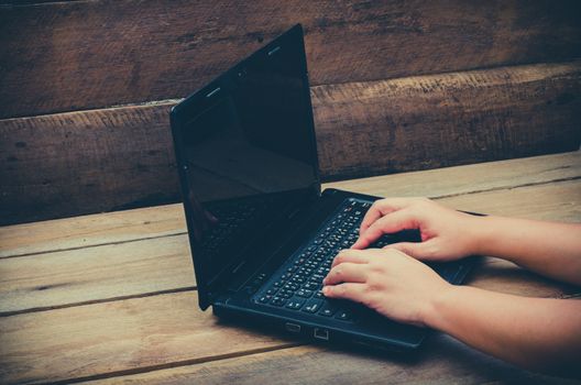 hands typing on laptop  on wooden background