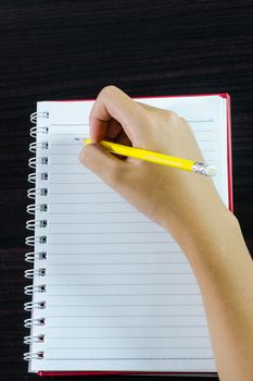 Hand writing in open notebook on table