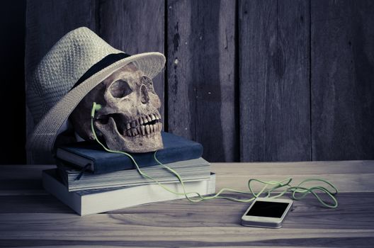 still life - skull have headphone on books and hat on wooden table