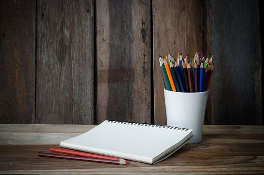 Color pencil and sketchbook on wood table