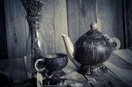 Kettle glass of water from coconut shells, dried flowers.on wooden background