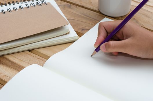 Hand writing in open notebook on table