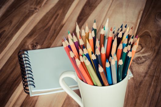 Color pencil and sketchbook on wood table