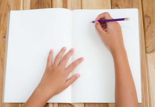 Hand writing in open notebook on table