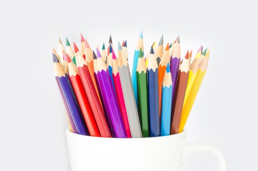 Stack of colored pencils in a glass on white background