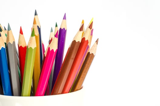 Close up stack of colored pencils in a glass on white background