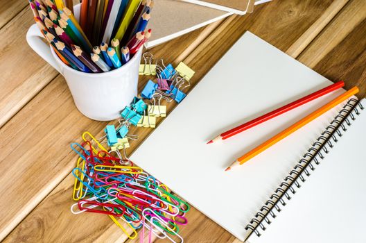 Colored pencils and notebook paper clip turnovers on a wooden table.
