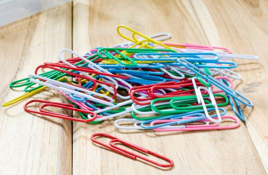 Colorful paper clips on a wooden table.