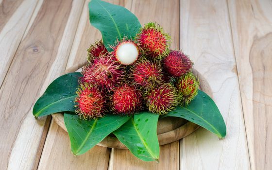 Red rambutan on wooden background.