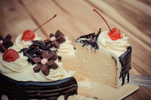 Birthday cake, vanilla Chocolate Cherry was divided pieces on a wooden table.