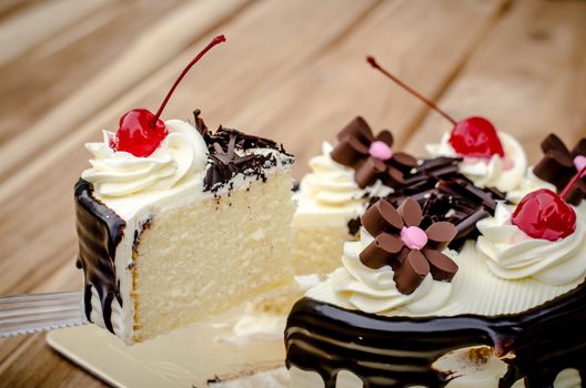 Birthday cake, vanilla Chocolate Cherry was divided pieces on a wooden table.