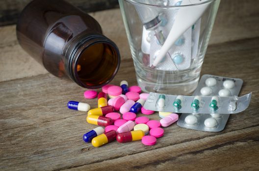 Various types of medicines, syringes and thermometers on wooden floor