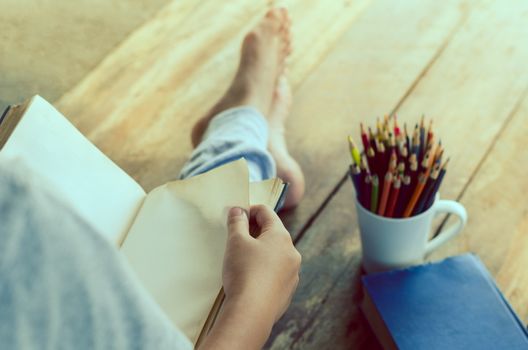 reading book on wooden floor with book and color pencil -tone vintage