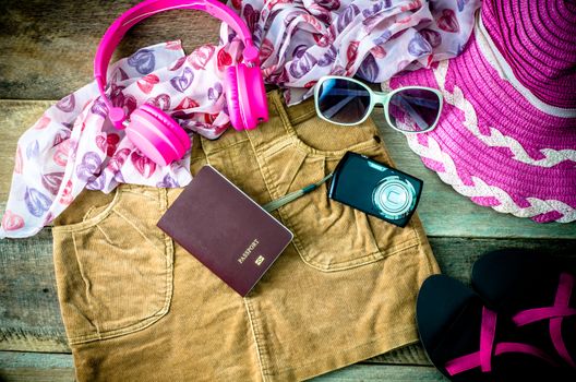 Travel accessories, headphones, camera, glasses, scarves, skirts, shoes, hat in preparation for the trip.