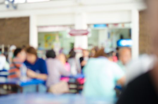 Blur image people enjoy different activities between meals in the cafeteria.