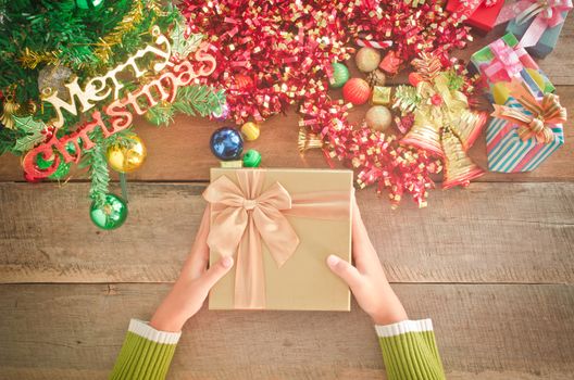 Handle Christmas gift box on a wooden table.