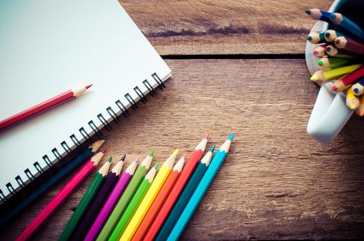 Color pencil and sketchbook on wooden background