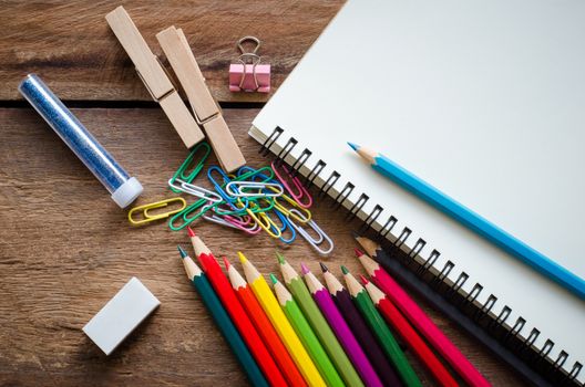 Crayons, erasers, notebook, clip on a wooden floor.