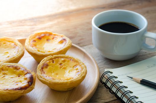 egg tart coffee notebook and pencil on the wooden table - tone vintage