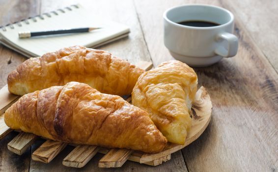 Croissants coffee notebook and pencil on the wooden table - tone vintage