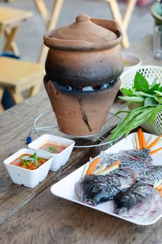 Dipping fish in boiled spicy soup in clay pot. Thai traditional style shabu