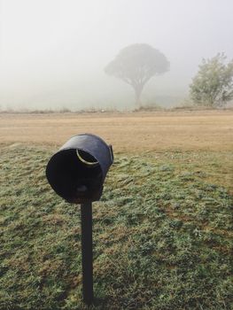 Foggy morning in rural Australia a simple tin can  mail box stands in the frosty grass
