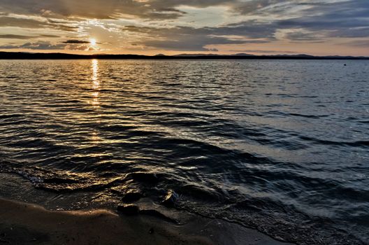 Golden sun sinks over the lake in the evening, golden water, South Ural lake Uvildy