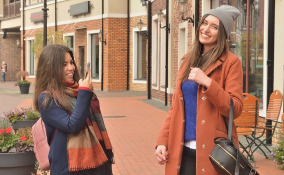 Two girls in coats walking around the city, smiling at each other