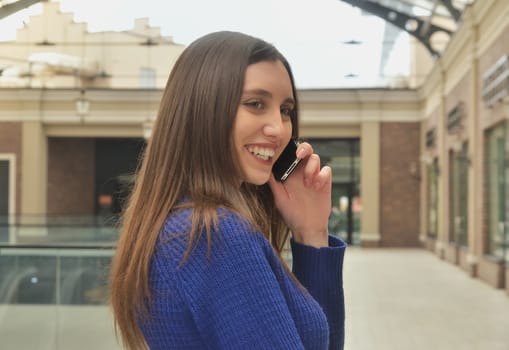 Portrait of a beautiful girl talking on the phone, walking shopping mall