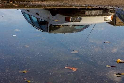 Car reflected in the water on the road, Latvia.