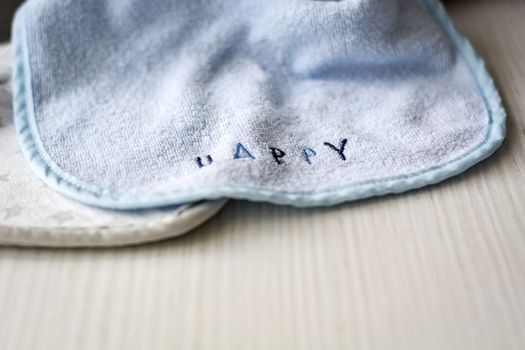 A baby bib with the word "HAPPY" resting on a white table