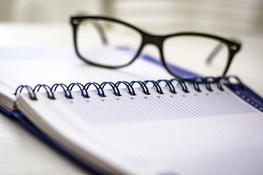 Eyeglasses on a blank spiral diary agenda. Business and time schedule concept