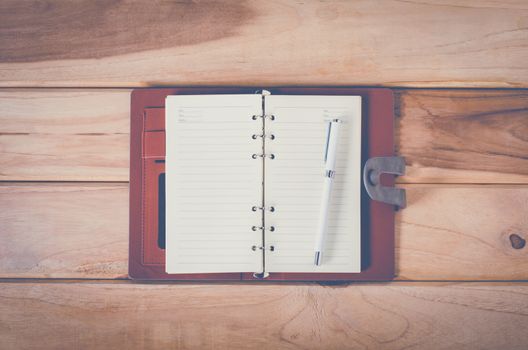 blank notebook with pen on wooden table