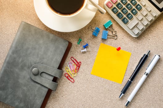Note placed on the table and a cup of coffee office supplies on the table.