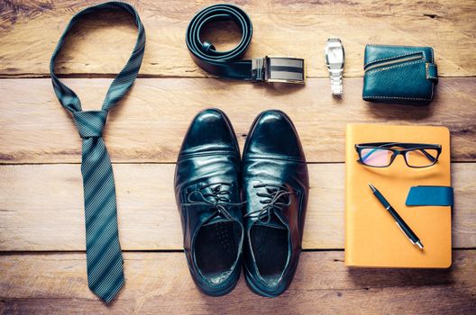Leather shoes and accessories for work lay on the wooden floor