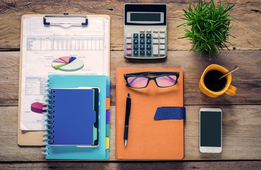 Graphing, calculators, notebooks, pens, coffee cup and eyeglasses on the wooden floor