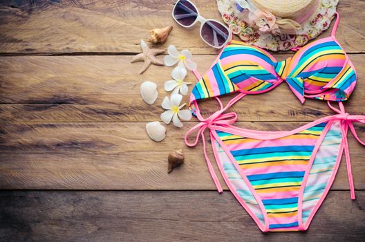 Beauty colorful bikini and accessories on wooden floor