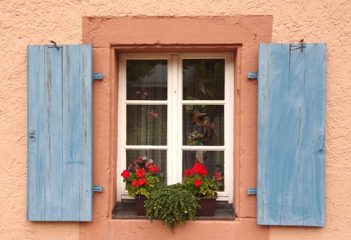 Flowered window with blue blinds on a pink wall, in Germany, Schiltach