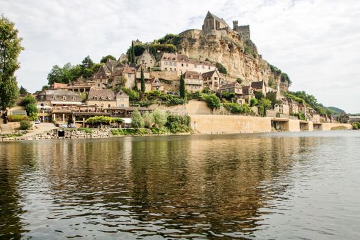 the village of beynac et cazenac with its medieval castle on the cliff reflecting in dordogne river