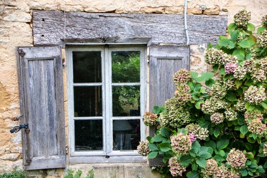 rustic wooden window on a stone wall at saint amand de coly , perigord noir in aquitaine, france