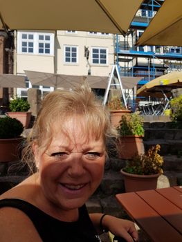 Lueneburg, Lower Saxony, Germany - JULY 28, 2017:
Woman sitting in the beer garden of a restaurant in Lüneburg and laughing in the camera