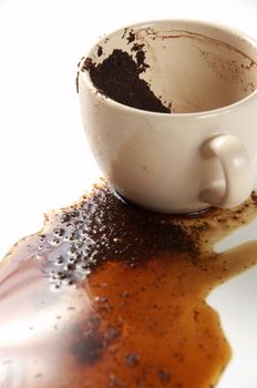 Spilled coffee and coffee grounds on a white background. Cup of coffee with coffee grounds.