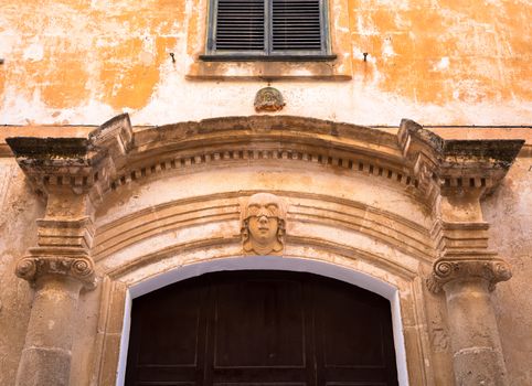 Gothic detail. Young woman portrait at the entrance of a 200 years old building in Ciutadella town, Menorca (Spain)