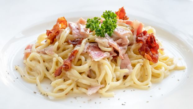 Spaghetti carbonara with bacon and cheese on white dish