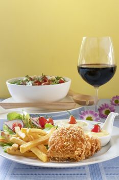 Deep fried fish steak served with french fries and fresh vegetables on white plate