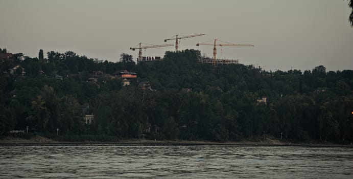 Three cranes on other side of river Danube