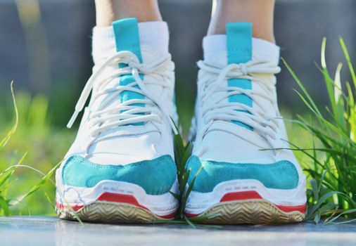 Girl in sneakers standing on the grass on a Sunny day direct view