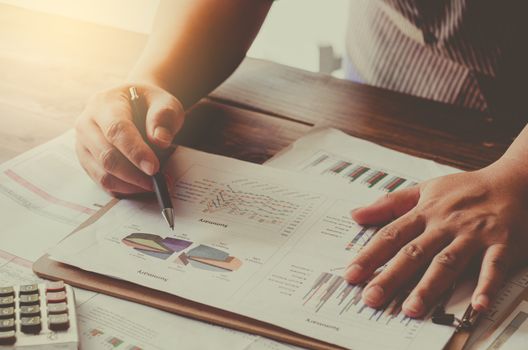 Businessman holding paperwork on the table and analyzing investment chart working in office. Business work concept. 